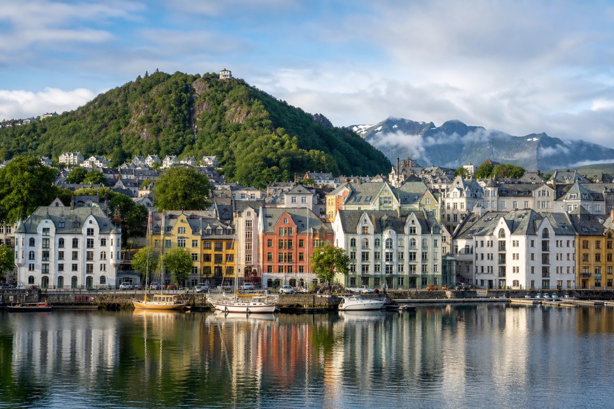 Jugendstil-Häuser am Hafen von Ålesund vor grünen Bergen